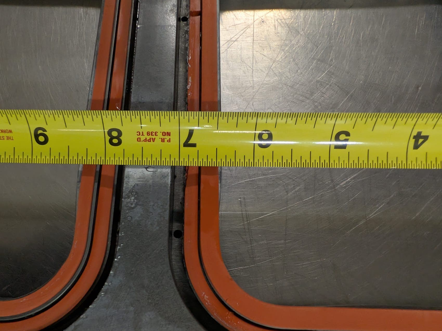 A stainless conveyor section under build in the shop, parts bins racked behind it