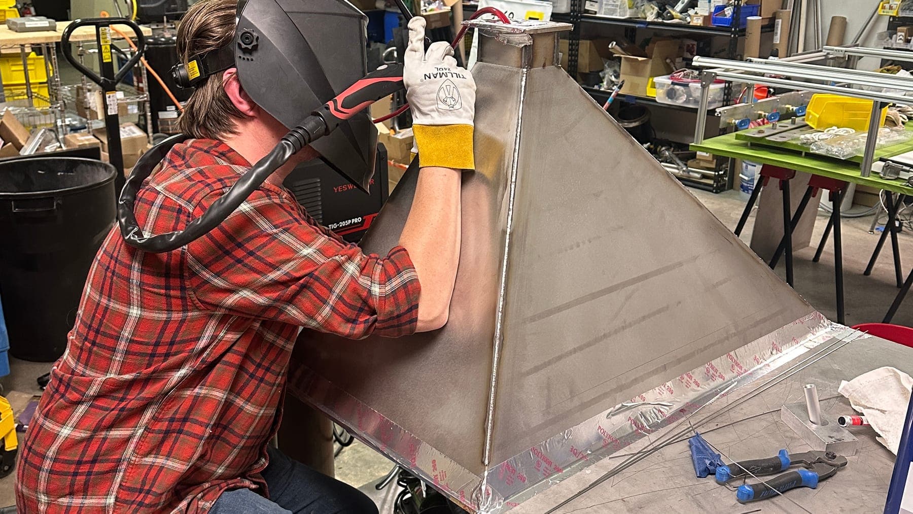 An engineer TIG-welding a stainless hopper cone on the bench in the Launch Partners shop