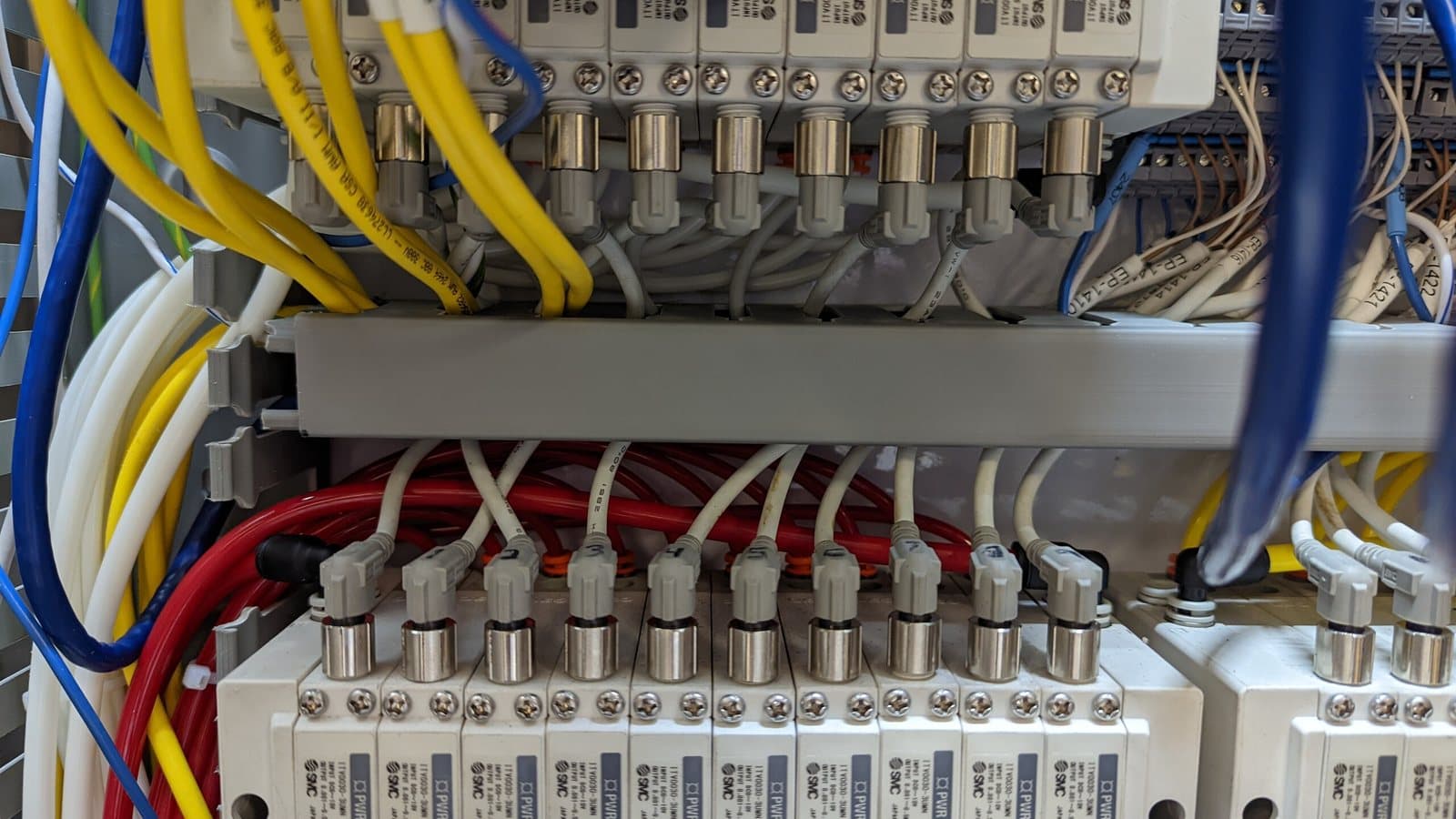 Close view of a pneumatic valve manifold bank with dressed yellow and red tubing