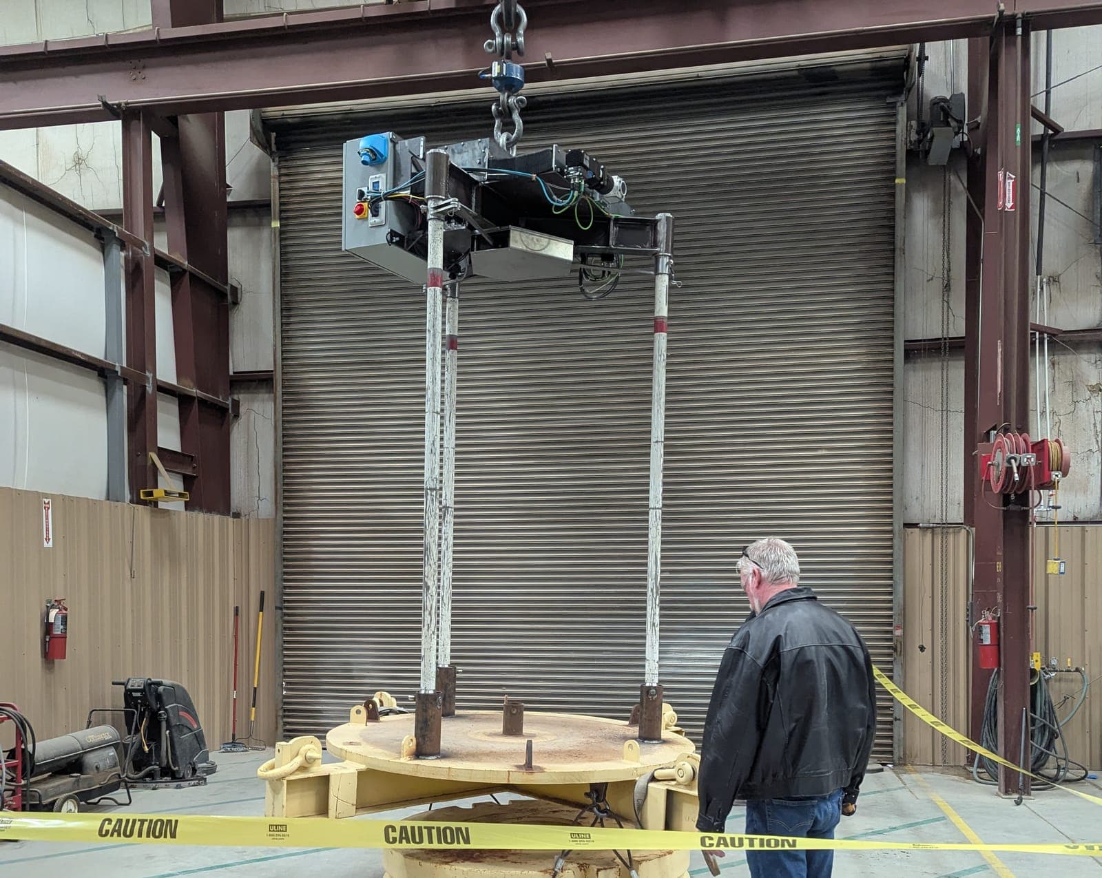 A large welded machine frame lifted by overhead crane during assembly