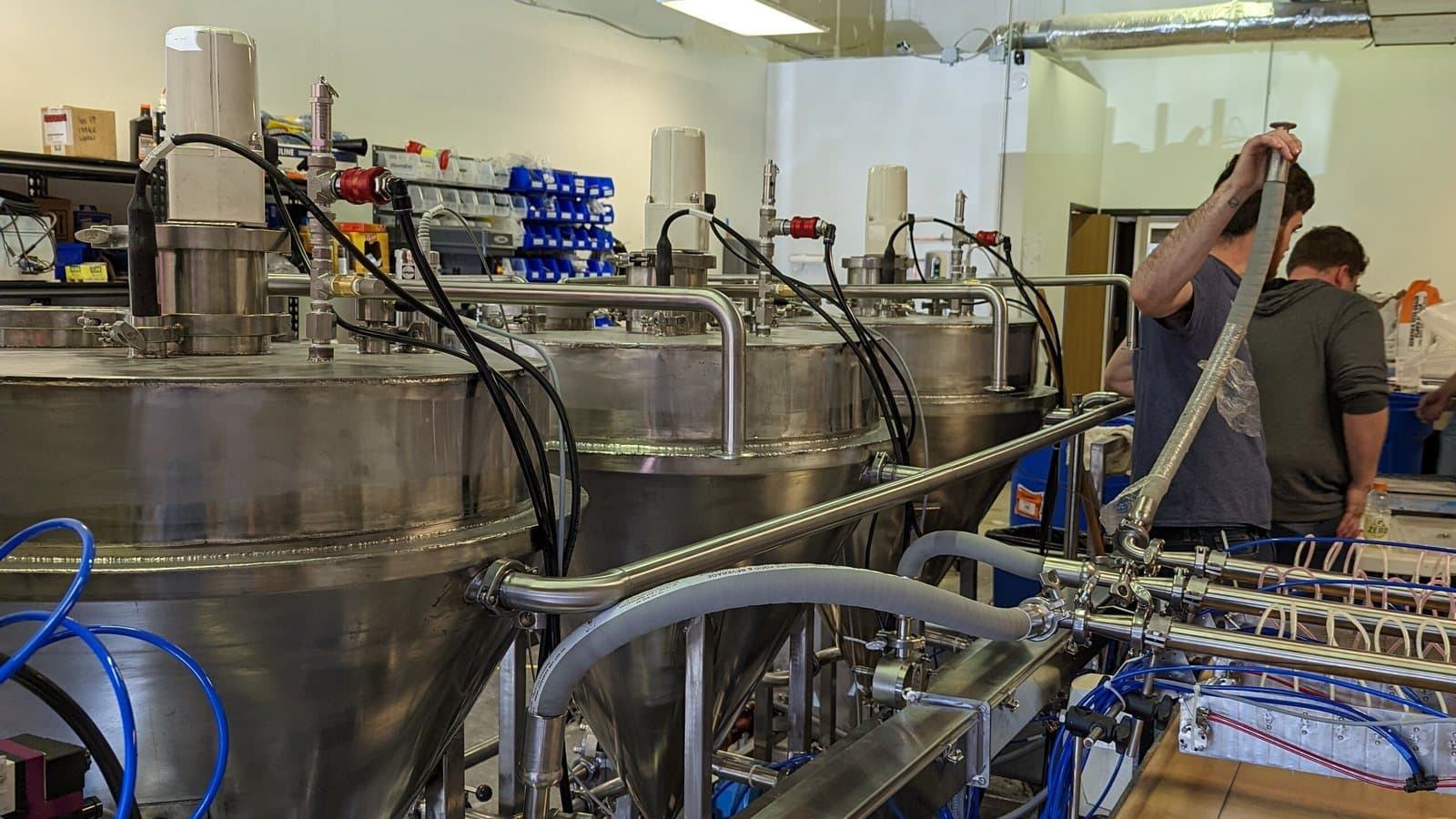 Two engineers assembling a multi-vessel stainless process machine