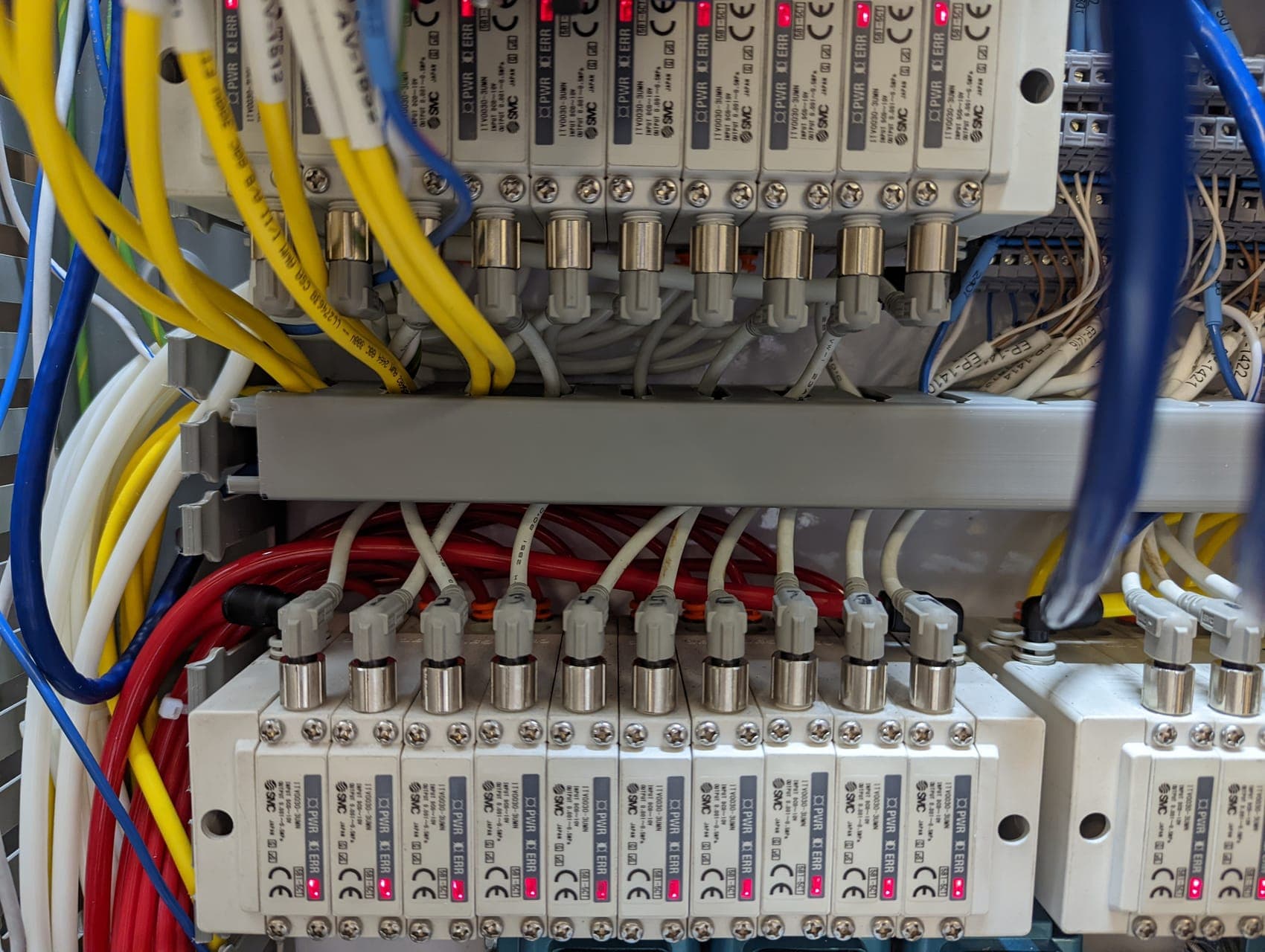 A bank of pneumatic valves on a manifold with colour-coded tubing and wiring, inside a machine enclosure